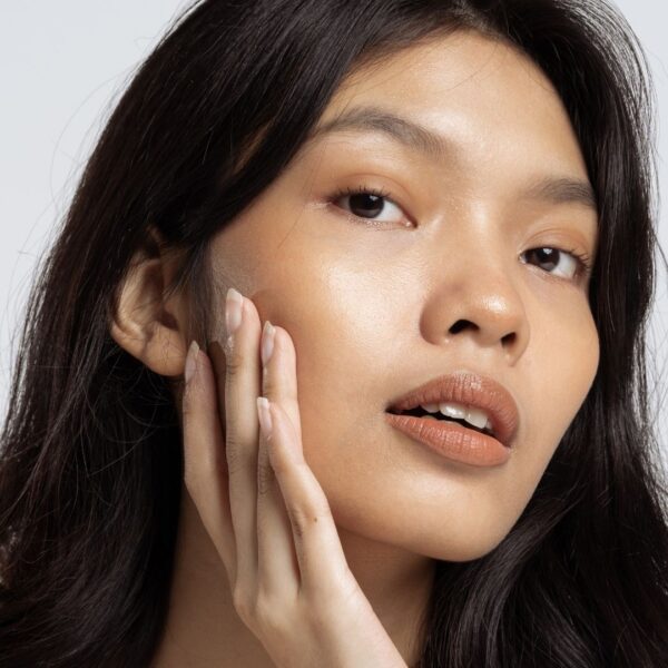 Mid-20s woman applying retinol to her skin.